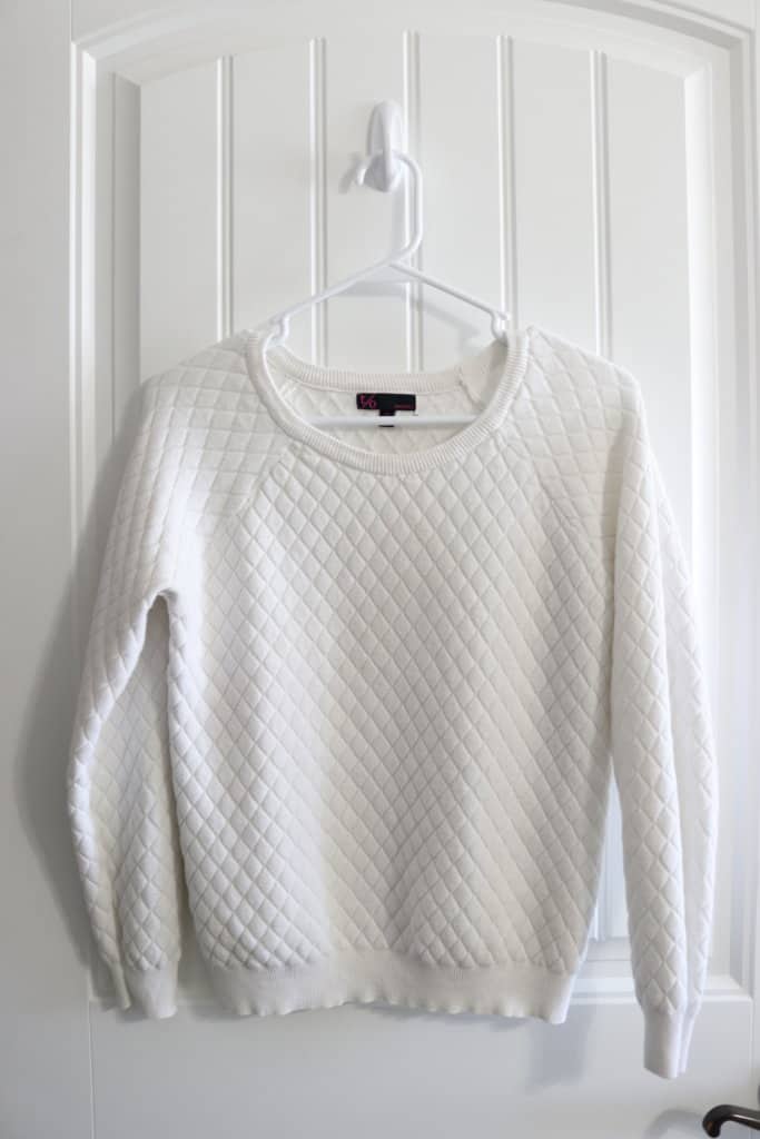 white sweater hanging up on door