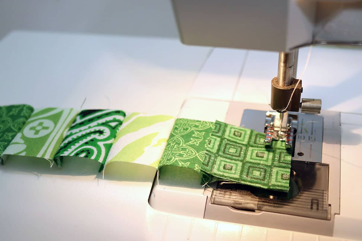 sewing machine sewing green squares together