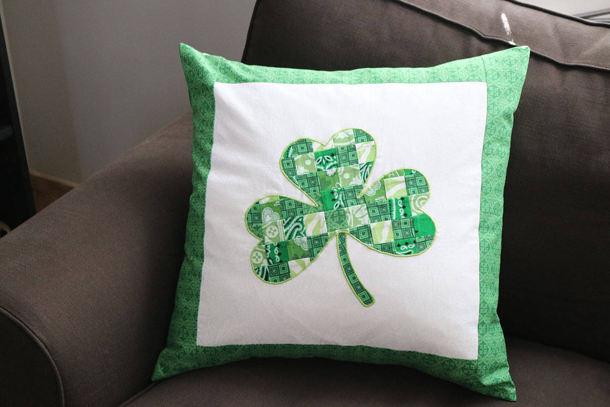 green and white shamrock applique pillow on brown couch