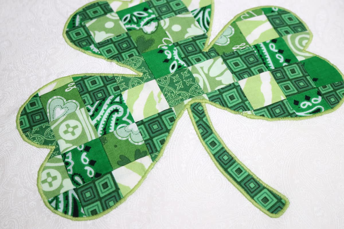 green pieced shamrock appliqued and embroidery stitched to white fabric