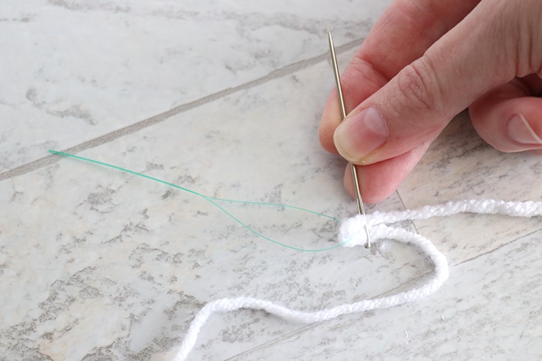 threading yarn onto a needle for a DIY ghost garland