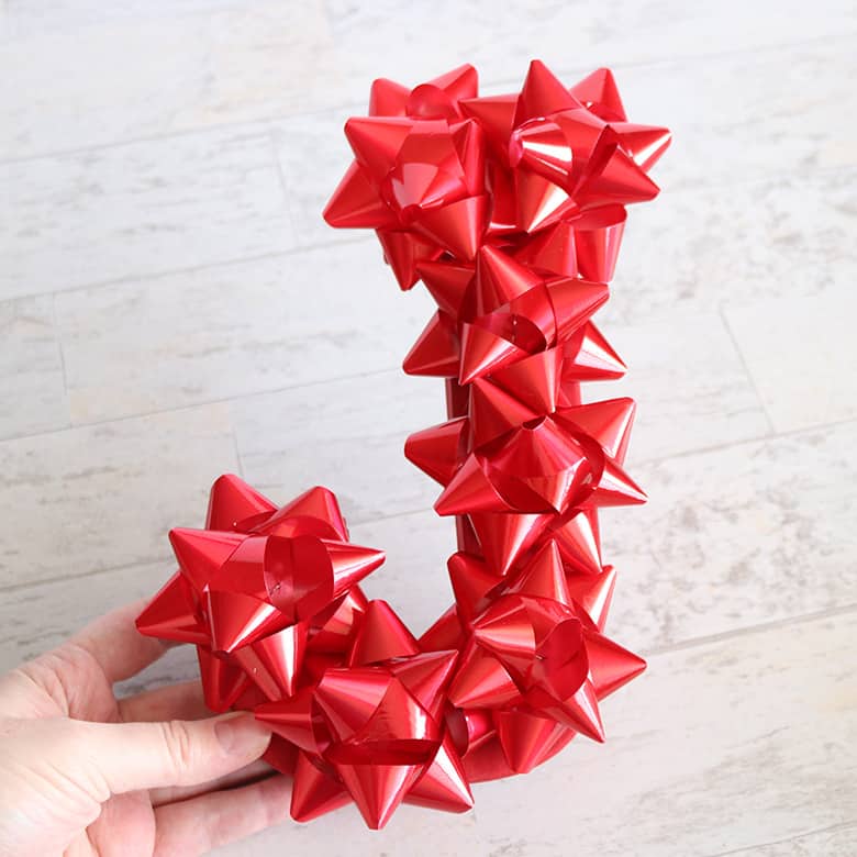 Christmas letters made with stick-on Christmas bows to spell "JOY"