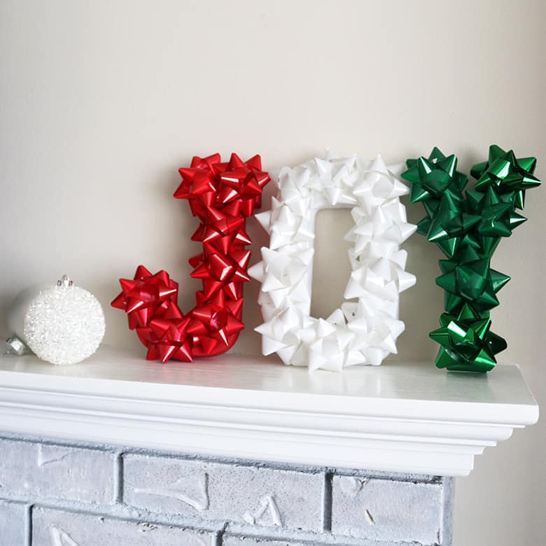 Christmas letters made with stick-on Christmas bows to spell "JOY"