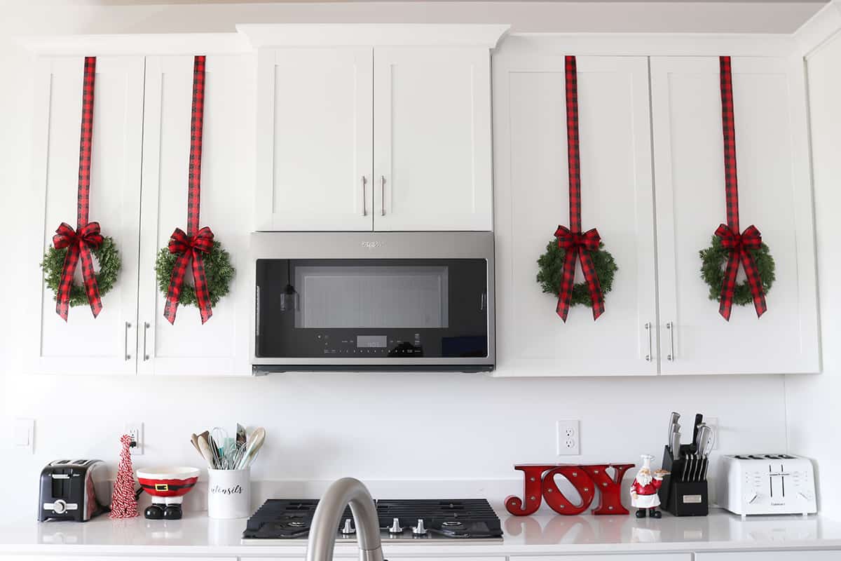 white kitchen with red buffalo plaid ribbon wreaths on cabinet doors, best size wreath for cabinets