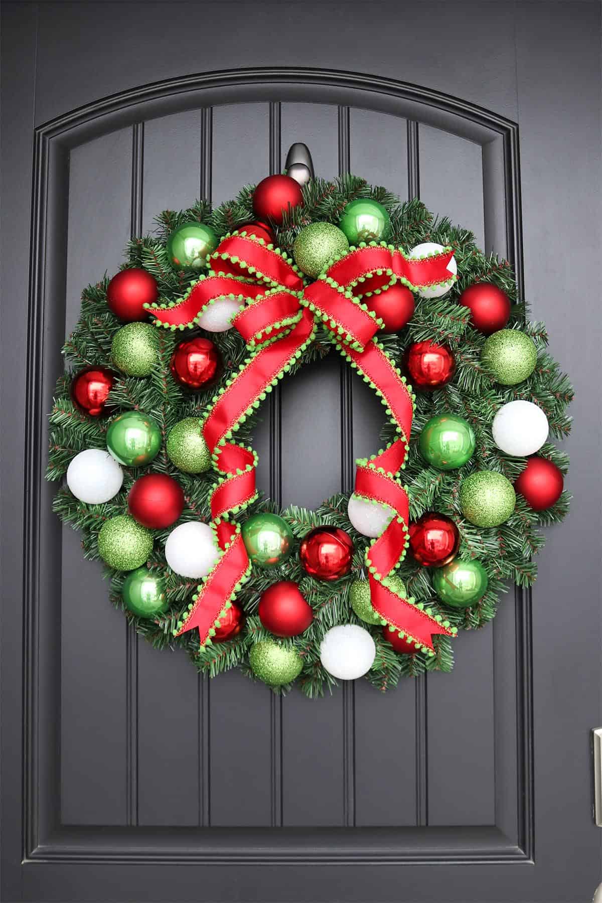 how to make an easy DIY Christmas ornament wreath, red green and white evergreen Christmas wreath hanging on black front door
